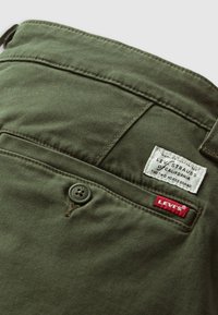 Green Levi's pants pocket with button closure, white Levi Strauss label, and red Levi's fabric tag.