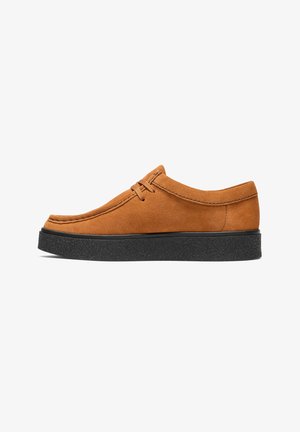 Chaussure décontractée en daim marron avec semelle épaisse noire et lacets à l'avant, vue de côté sur fond blanc.