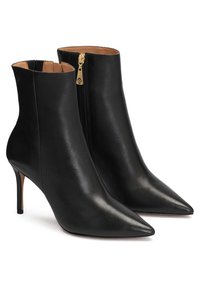 Botas de cuero negro hasta el tobillo con puntera puntiaguda, tacón de estilete y cremallera lateral con detalles en dorado. Textura suave con un diseño elegante.