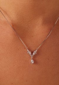 El collar de plata presenta un diseño en forma de V con piedras claras en corte pera y marquesa, acentuadas por pequeñas piedras redondas, colgante.