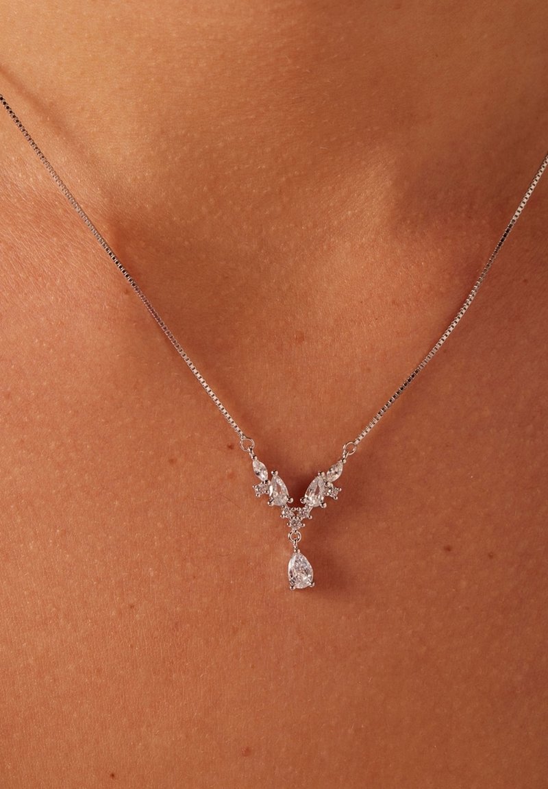 El collar de plata presenta un diseño en forma de V con piedras claras en corte pera y marquesa, acentuadas por pequeñas piedras redondas, colgante.