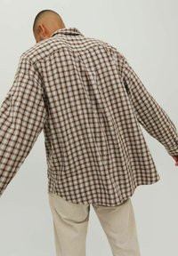 Brun og creme plaid skjorte med afslappet pasform, lange ærmer og skjortekrave. Lavet af struktureret stof med synlige sømdetaljer.