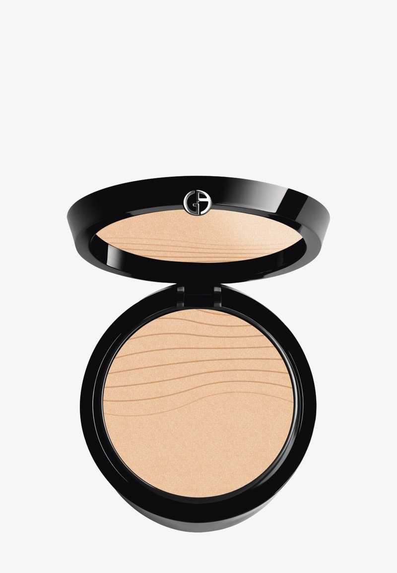 Poudre compacte dans un boîtier circulaire noir. La poudre est beige clair avec une texture lisse et un subtil motif en vagues à la surface.