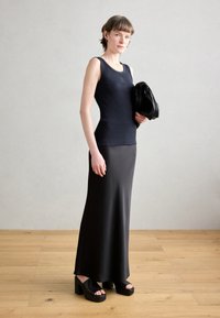 Top in tessuto a costine nero abbinato a una gonna nera lunga fino al pavimento e sandali platform neri spessi. Tiene una clutch nera. Tessura liscia.