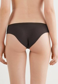 Bruna bomullstrosor med låg midja, slät textur och sömlösa kanter. Inga synliga mönster eller metalldelar.