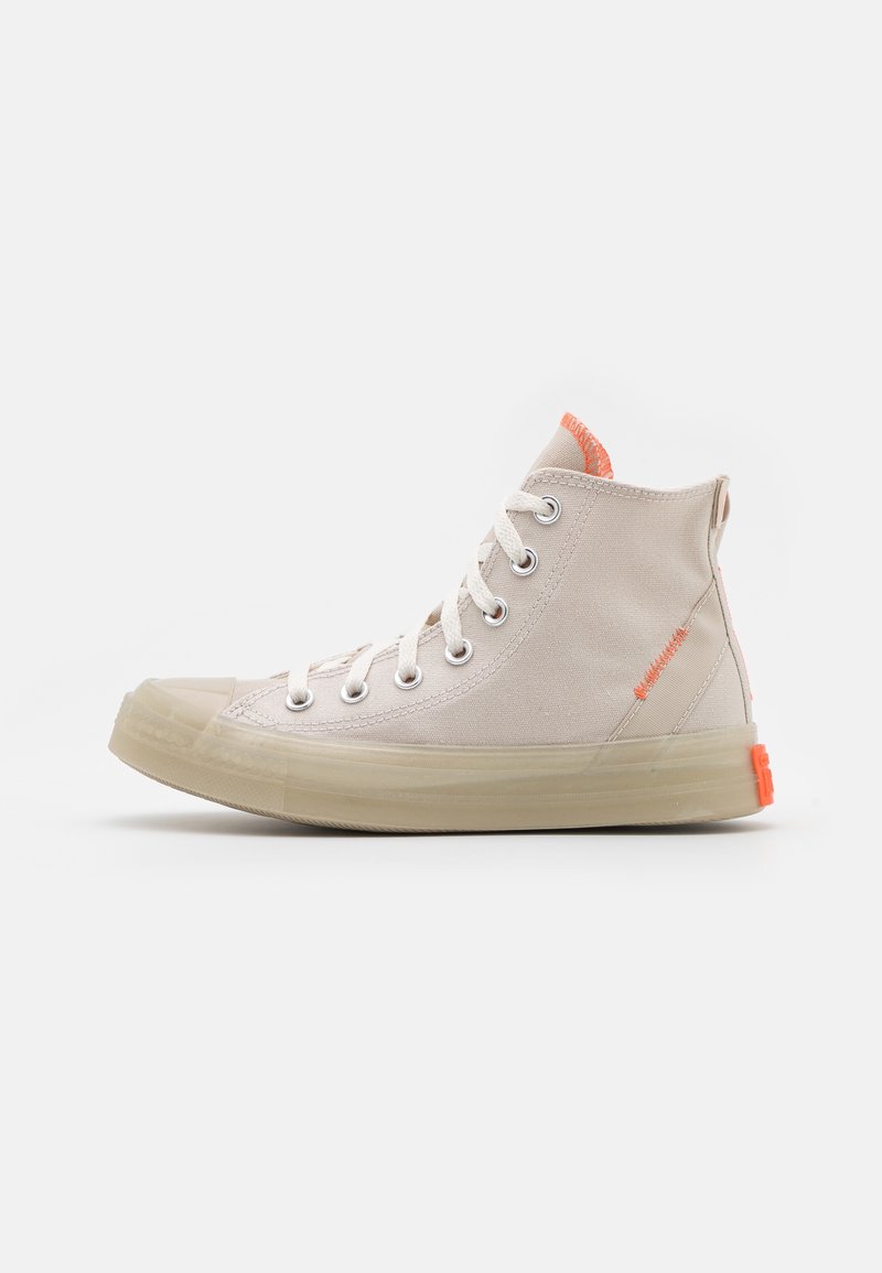 Höga beige canvas sneakers med vita snören, transparent gummisula och orange detaljer på hälen och kragen. Klassisk rund tådesign.