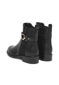 Čierne kožené členkové čižmy s hladkým povrchom, so zlatou prackou na boku a nízkym, pevným podpätkom.