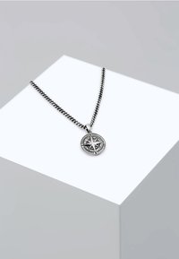 Sidabrinė vėrinio grandinėlė su apvaliu pakabuku, kuriame pavaizduota kompaso dizaino motyvas su išsamiais ornamentais, pakabintas ant pintos grandinėlės.