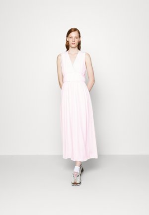 Lyserød ærmeløs maxikjole har en V-udskæring, samlet talje og blød tekstur. Båret med sølvfarvede og beige sneakers samt hvide sokker.