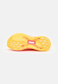 Semelle de chaussure de course jaune et orange avec des motifs de grip rectangulaires et une découpe centrale visible sur fond blanc.