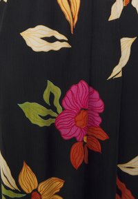 Schwarzer Stoff mit buntem floralen Muster, das pinke, orangefarbene und gelbe Blumen sowie grüne Blätter zeigt, mit sichtbarer Textur und Stofffalten.