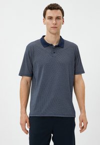 Camisa polo Navy con un cuello azul oscuro en contraste, mangas cortas, una botonera y una tela texturada con patrón.