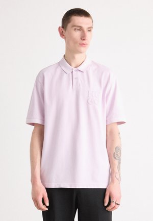Light purple polo shirt with a buttoned collar, short sleeves, and an embroidered "HUGO" logo on the chest. Smooth cotton material.