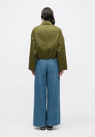 Πράσινο cropped σακάκι με δομημένο γιακά, συνδυασμένο με φαρδιά ανοιχτό μπλε τζιν. Υφασμάτινο βαμβάκι με υφή· casual, άνετη εφαρμογή.