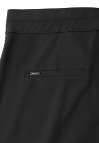 Pantalones negros con una textura suave, una cinturilla con detalles de costura y un bolsillo trasero con una pequeña etiqueta de marca.