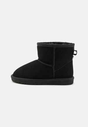Botte de cheville en daim noir avec un bout arrondi, texture lisse et tige courte. Dotée d'une boucle à l'arrière pour un enfilage facile et d'une doublure intérieure douce.
