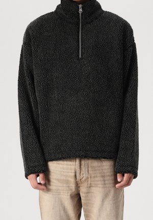 Schwarzer Fleece-Pullover mit hohem Kragen, Reißverschluss vorne und langen Ärmeln. Strukturierte Oberfläche mit einem weichen, flauschigen Aussehen. Lässige Passform.