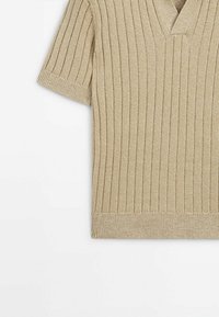 Haut en tricot beige à côtes à manches courtes avec un décolleté en V, présentant un tissu texturé et une coupe ajustée.