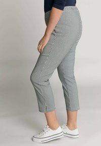 Pantaloni alla caviglia in bianco e nero con motivo houndstooth, dotati di vita aderente, fessure laterali e un tessuto morbido e elasticizzato. Abbinati a sneakers bianche.
