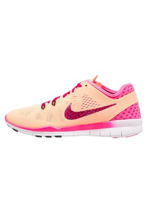 Zapatilla de running Nike de color naranja claro y rosa con malla transpirable, diseño agrietado rosa en el logo Swoosh y suela blanca, mostrada de perfil.