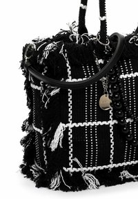 Czarna i biała pleciona torebka tekstylna z postrzępionymi krawędziami, o zwartej formie, z czarnym paskiem i ozdobnymi koralikami.