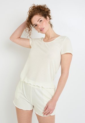 Top corto a manica corta di colore chiaro con righe e pantaloni coordinati con orli ondulati; texture morbida; stile loungewear casual.
