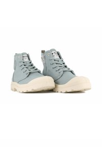 Sneaker alte in tela azzurro chiaro con suole in gomma crema e punta tonda. Presentano lacci e una cerniera laterale per una facile vestibilità.