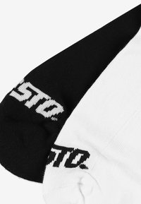 Czarno-białe bawełniane skarpetki o kontrastujących kolorach, z teksturowanym wykończeniem i wyraźnym czarnym logo marki.