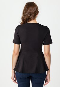 Czarny top peplum z krótkimi rękawami, wykonany z gładkiego materiału. Posiada dopasowaną górę i rozkloszowany dół, co tworzy zorganizowaną sylwetkę.