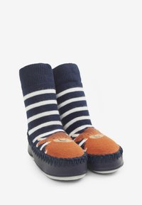 Stribede navy og hvide strikstrømper har en orange stoftå med et løveansigt design, suppleret med en mørkeblå lædersål.