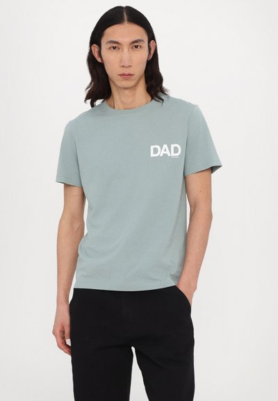 Hele roheline t-särk, mis on valmistatud puuvillast ja millel on lühikesed varrukad, vasakul rinnal on valge "DAD" graafika. Ühildub mustade pükstega.