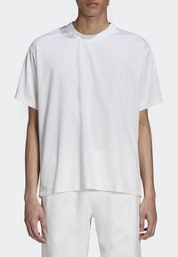 Bílý krátký rukáv tričko vyrobené z měkké látky, s kulatým výstřihem a jemným vzorovaným designem. Uvolněný střih s rovným zakončením.