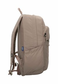 Mochila beige con una textura suave, bolsillos laterales, correas ajustables y un asa superior, que presenta un diseño minimalista.