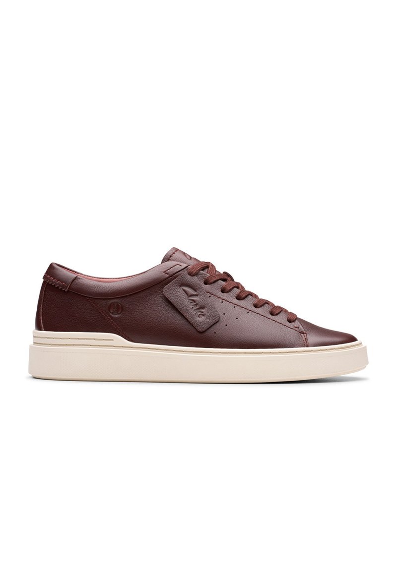 Sneaker in pelle bordeaux con una finitura liscia, punta tonda, suola piatta color crema e lacci tonali. Presenta un piccolo tag con il marchio sul lato.