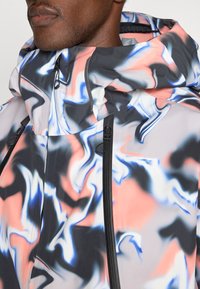 Giacca colorata con un motivo vorticoso di rosa, blu e nero. Realizzata in materiale liscio con colletto alto e cerniere.