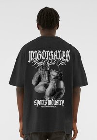 Sort oversized t-shirt med et grafisk motiv af boksehandsker og fed tekst på ryggen, lavet af bomuld med en blød tekstur.