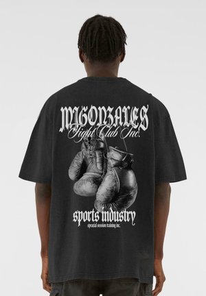 Sort oversized t-shirt med et grafisk motiv af boksehandsker og fed tekst på ryggen, lavet af bomuld med en blød tekstur.