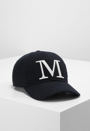 Casquette de baseball noire avec une grande lettre "M" blanche brodée à l'avant, posée sur une surface blanche avec un fond uni.