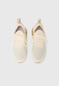 Ζευγάρι μπεζ αθλητικών παπουτσιών Nike Air 270 με δεμένα κορδόνια, σε θέα από πάνω, σε απλό λευκό φόντο.