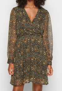 Robe transparente à manches longues en marron avec un motif abstrait coloré en bleu, or et blanc. Présente un décolleté en V et une taille cintrée.