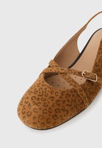 Chaussure slingback en suède marron avec imprimé léopard, bout rond, sangle croisée et détail de boucle dorée. Texture douce et semelle intérieure rembourrée.