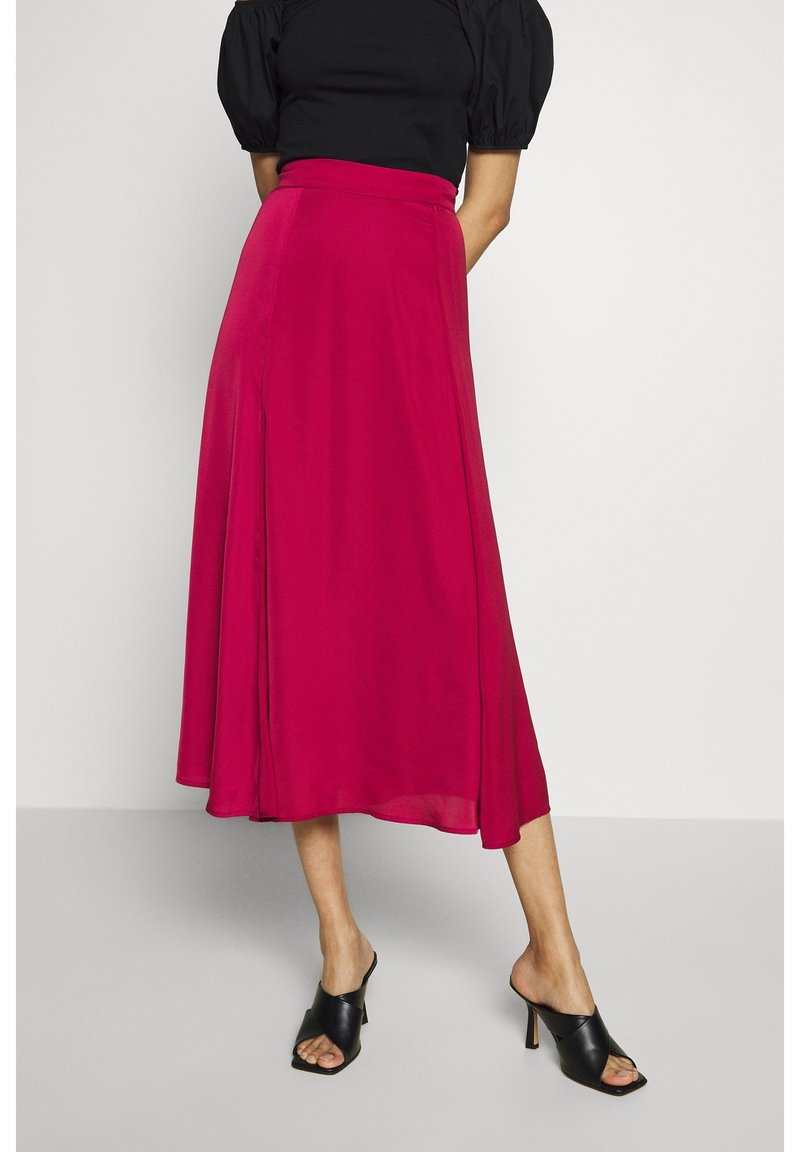 Fuchsia, knie-lange rok gemaakt van vloeiend materiaal met een gladde textuur, met een aansluitende taille en een lichte zijsplit. Draagt het met zwarte open-toe hakken.