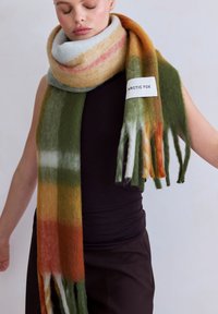 Écharpe en laine avec un motif dégradé aux tons vert, orange, jaune et gris ; finie avec des franges et une étiquette blanche.