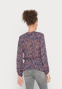 Blusa a manica lunga di colore blu con un motivo floreale in rosa e bianco. Leggera, con vita arricciata e una texture leggermente trasparente, con polsini elastici.