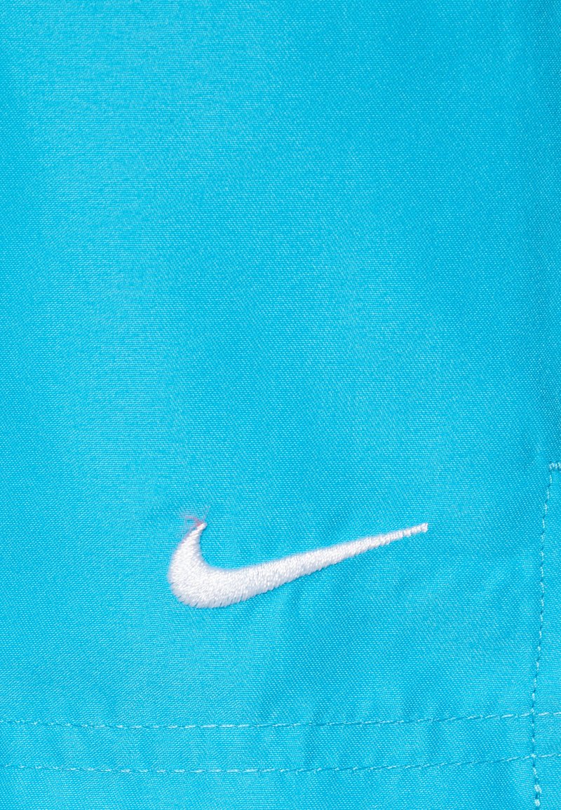 Nike-Stoff in strahlendem Blau mit einem weißen, gestickten Swoosh-Logo. Glatte Textur mit genähten Details entlang der Naht.