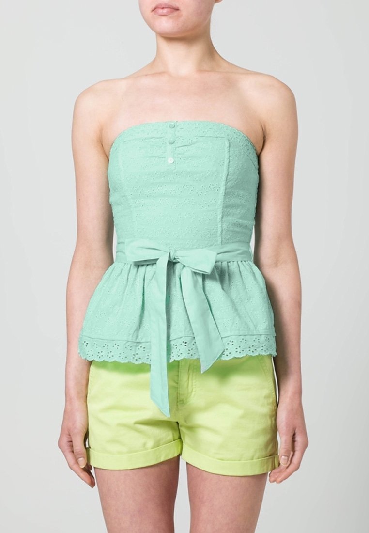 Top senza spalline verde menta con texture ad occhiello, design a peplum, cuciture verticali e un fiocco in vita; abbinato a pantaloni corti giallo chiaro.