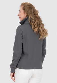 Pullover in pile grigio con maniche lunghe, chiusura a zip e colletto alto, dotato di polsini a coste. Texture liscia, design semplice e senza motivi visibili.