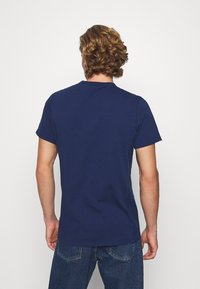 Camiseta de manga corta azul marino con cuello redondo, hecha de suave tela de algodón, que presenta un diseño simple y limpio sin adornos.