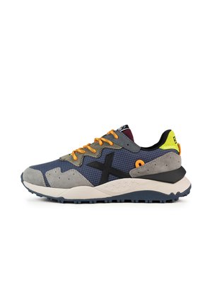Zapatillas deportivas en gris, azul marino y naranja. Materiales mixtos con malla y gamuza, con una gruesa suela blanca y una base de tracción de goma.