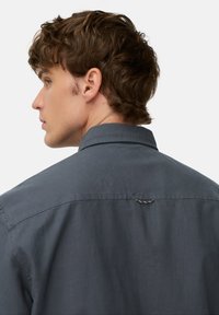 Donkergrijs overhemd met knoopjes, voorzien van een klassieke kraag, een subtiele textuur en een kenmerklabel aan de achterkant. Eenvoudig ontwerp, geen patronen.